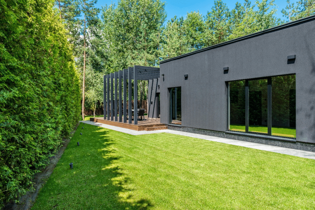 Exterior of gray house along with some backyard landscaping and a pergola